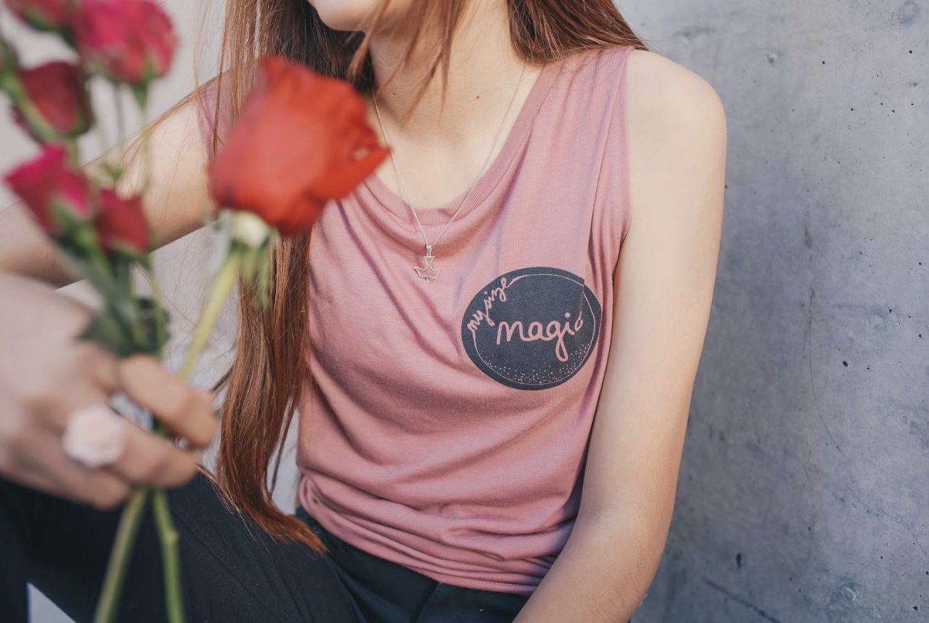 女士穿著粉色背心，手拿紅玫瑰，象徵浪漫與自我接納